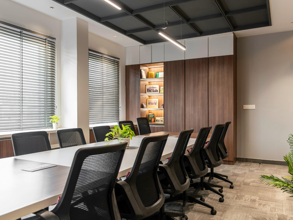 Moderne vergaderruimte met lange tafel, bureaustoelen, houten wandkasten en grote ramen met jaloezieën