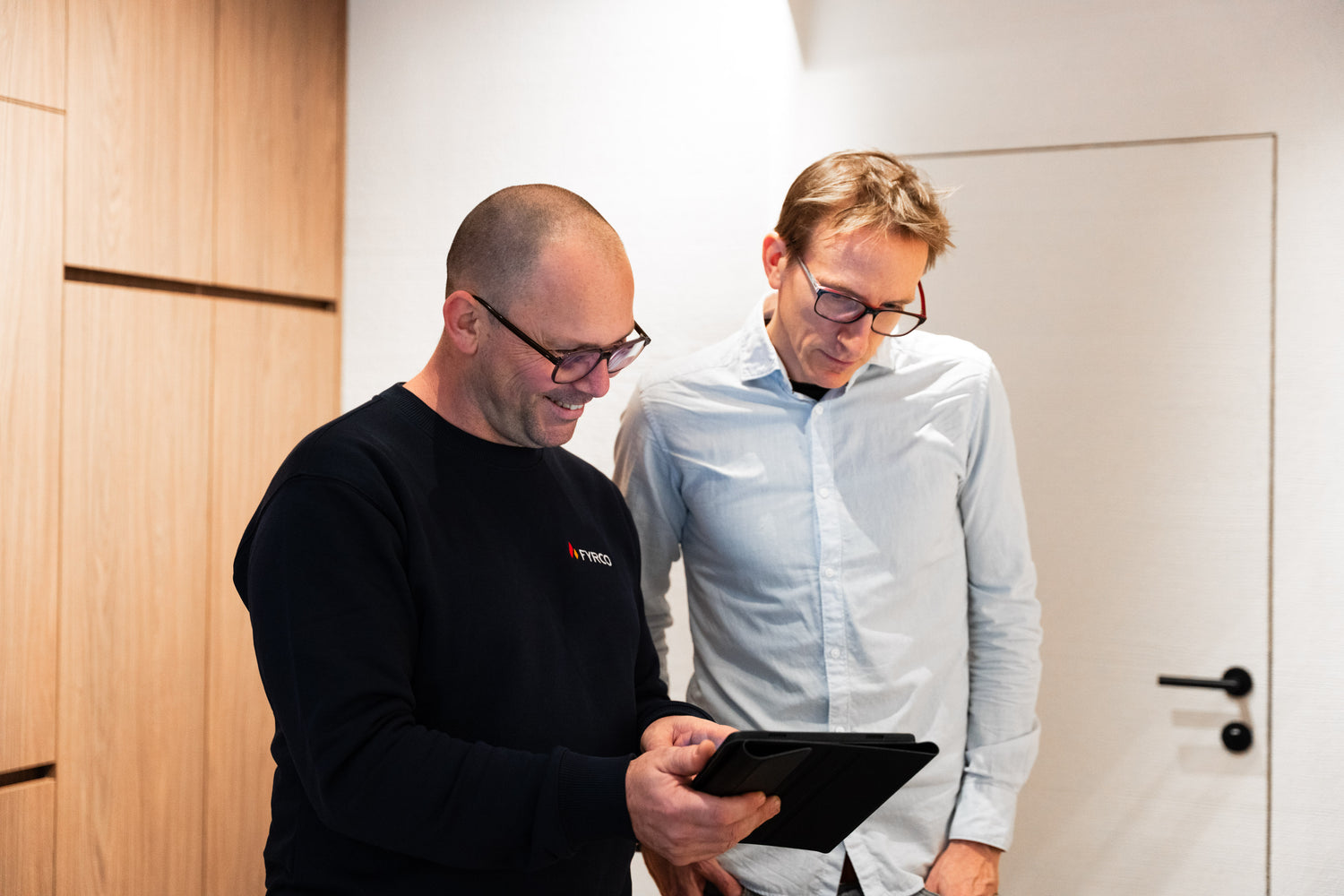 Technieker van FYRCO die samen met een klant de werkbon bekijkt op een tablet tijdens een interventie.