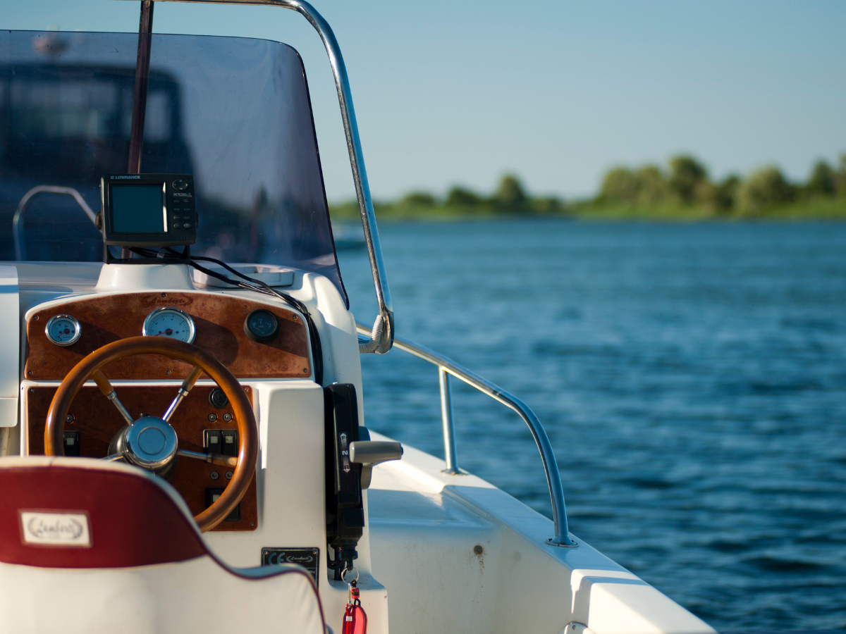 Stuur van een motorboot op het water met een zonnig landschap op de achtergrond