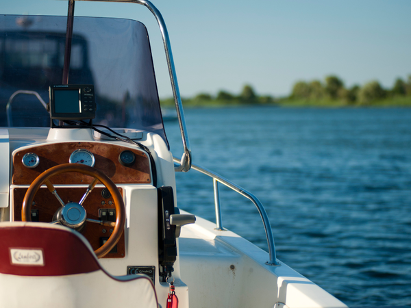 Stuur van een motorboot op het water met een zonnig landschap op de achtergrond