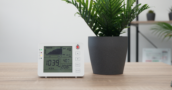 CO2-meter op tafel naast plant in een kantoorgebouw