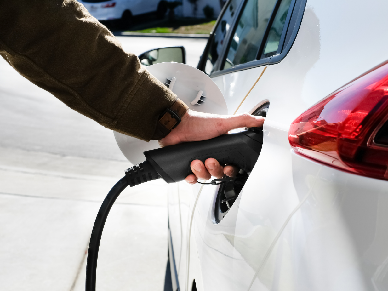 Persoon sluit een laadkabel aan op een witte elektrische auto