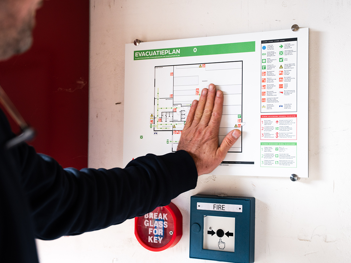 FYRCO-technieker hangt evacuatieplan op aan muur