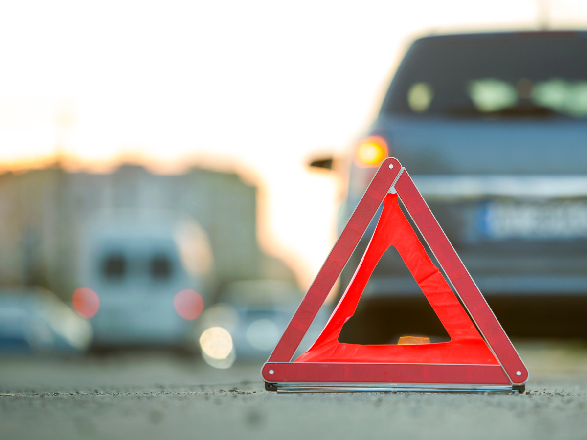 Gevarendriehoek op de weg achter een auto met pech