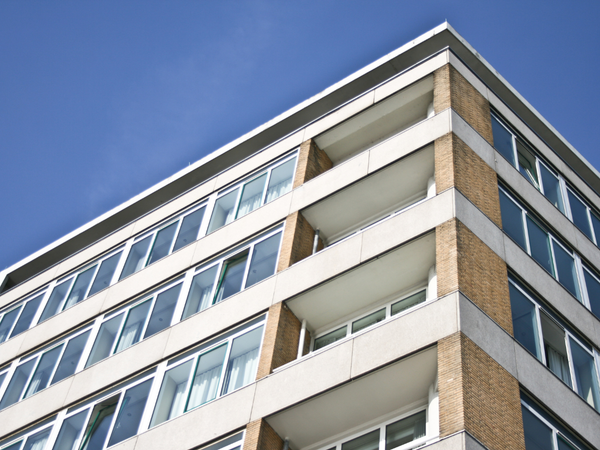 Modern appartementsgebouw met meerdere verdiepingen en balkons tegen een blauwe lucht