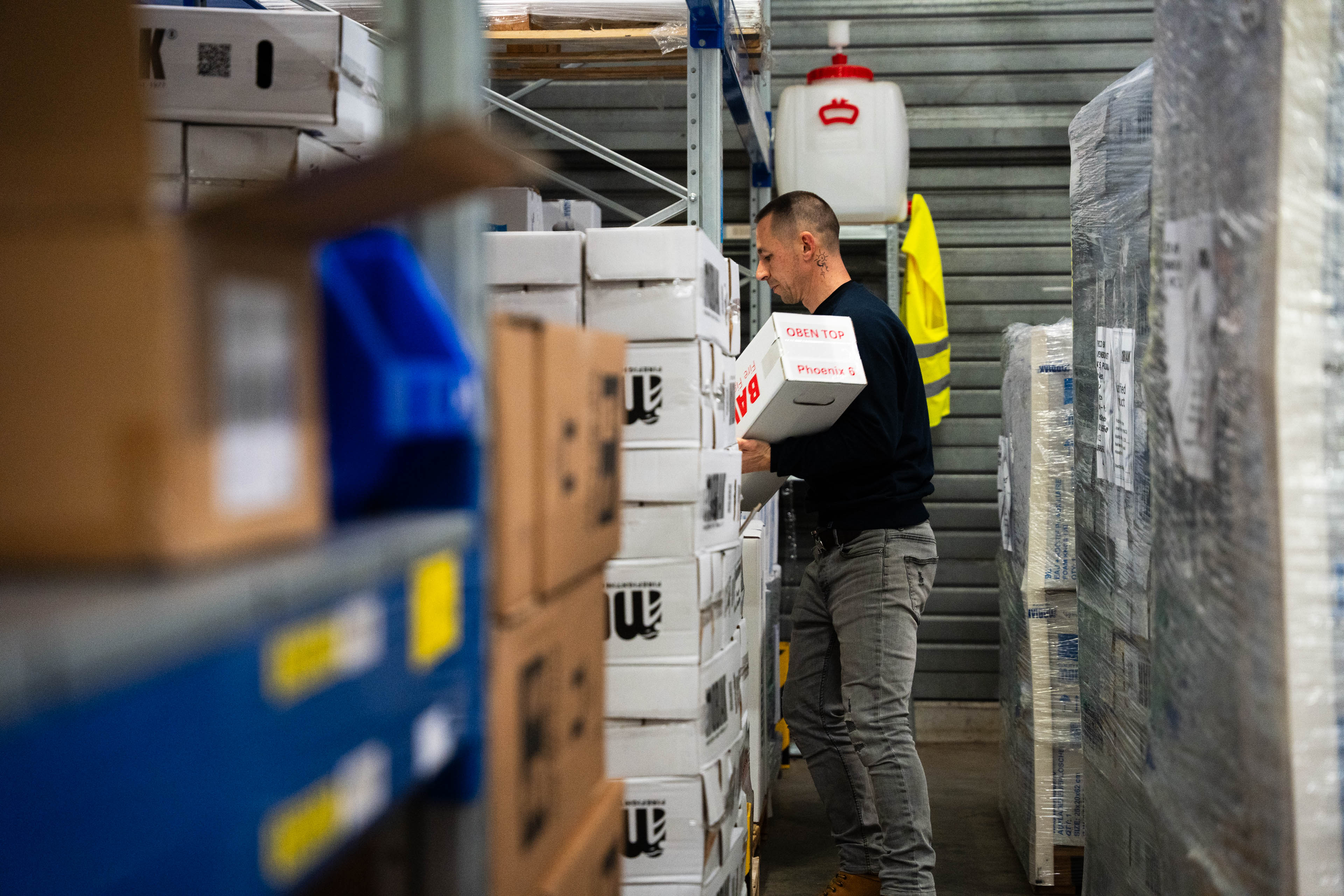 Medewerker die bestellingen verzamelt in een magazijnomgeving met rekken en dozen.
