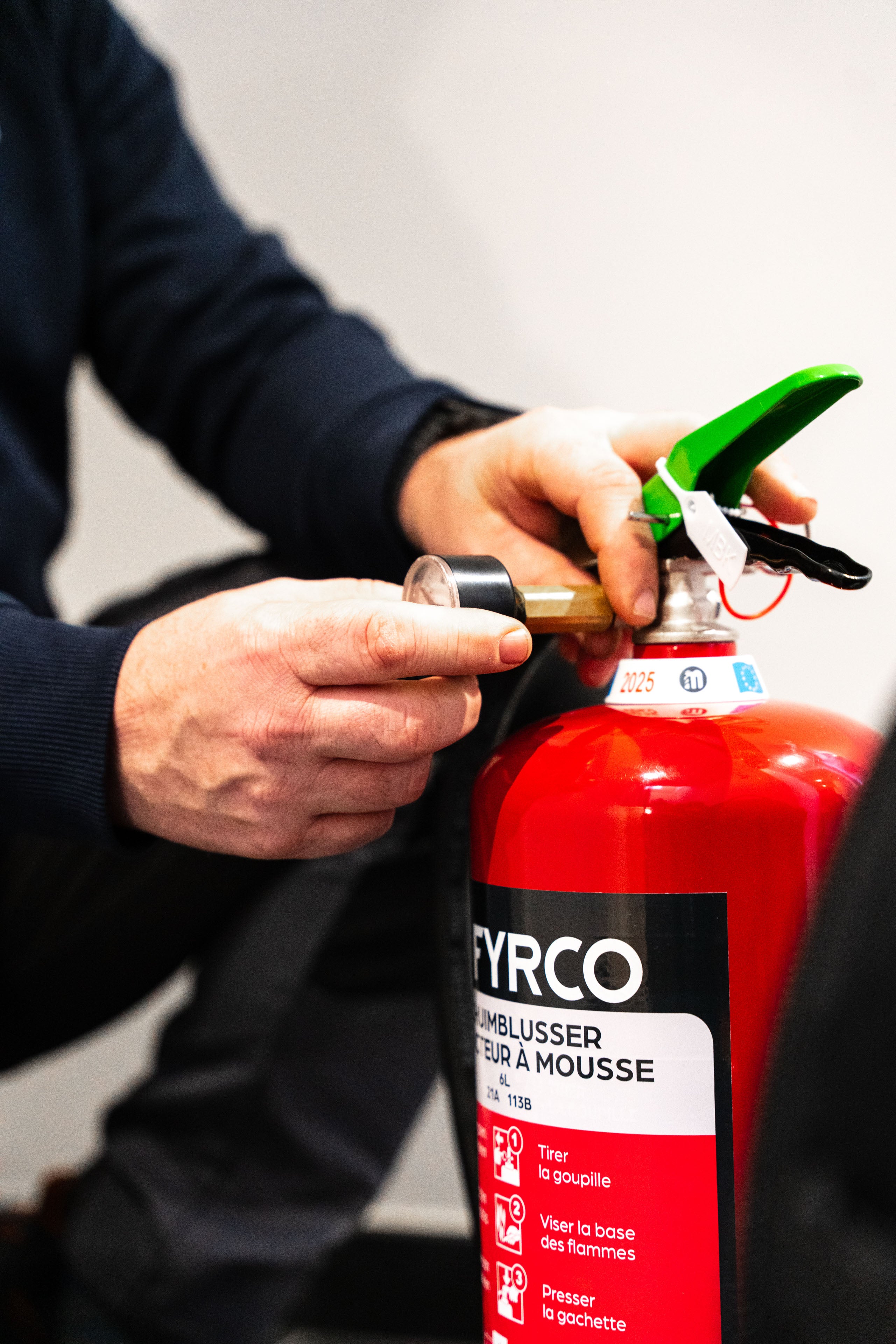 Technieker van FYRCO controleert de druk van een brandblusser tijdens periodiek onderhoud