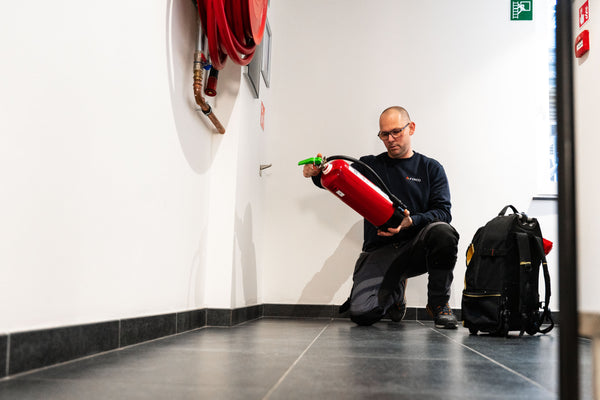 FYRCO-technieker controleert en onderhoudt een brandblusser in een gang bij een klant.