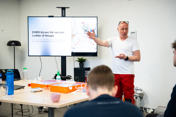 Opleider geeft EHBO-cursus aan de hand van een presentatie en EHBO koffer