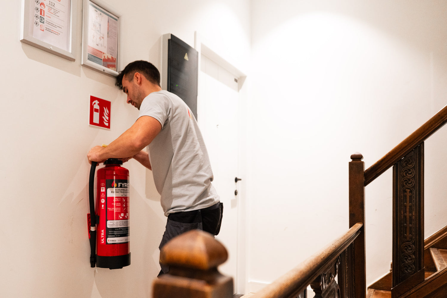 FYRCO-technieker hangt een brandblusser aan een muurbeugel
