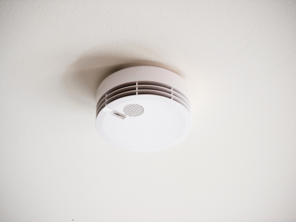 Witte rookmelder hangt op aan witte plafond