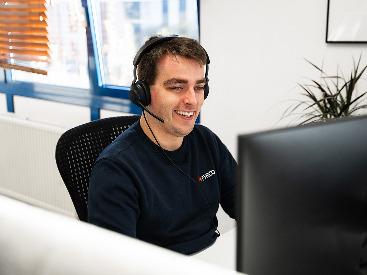 Glimlachende FYRCO sales advisor met headset die klanten telefonisch adviseert vanop kantoor