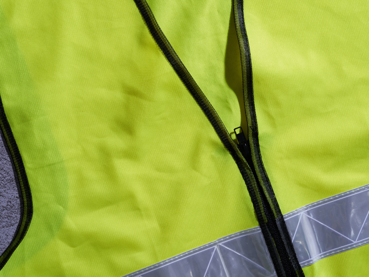 Close-up van een fluorescerend veiligheidshesje met ritssluiting en reflecterende strook