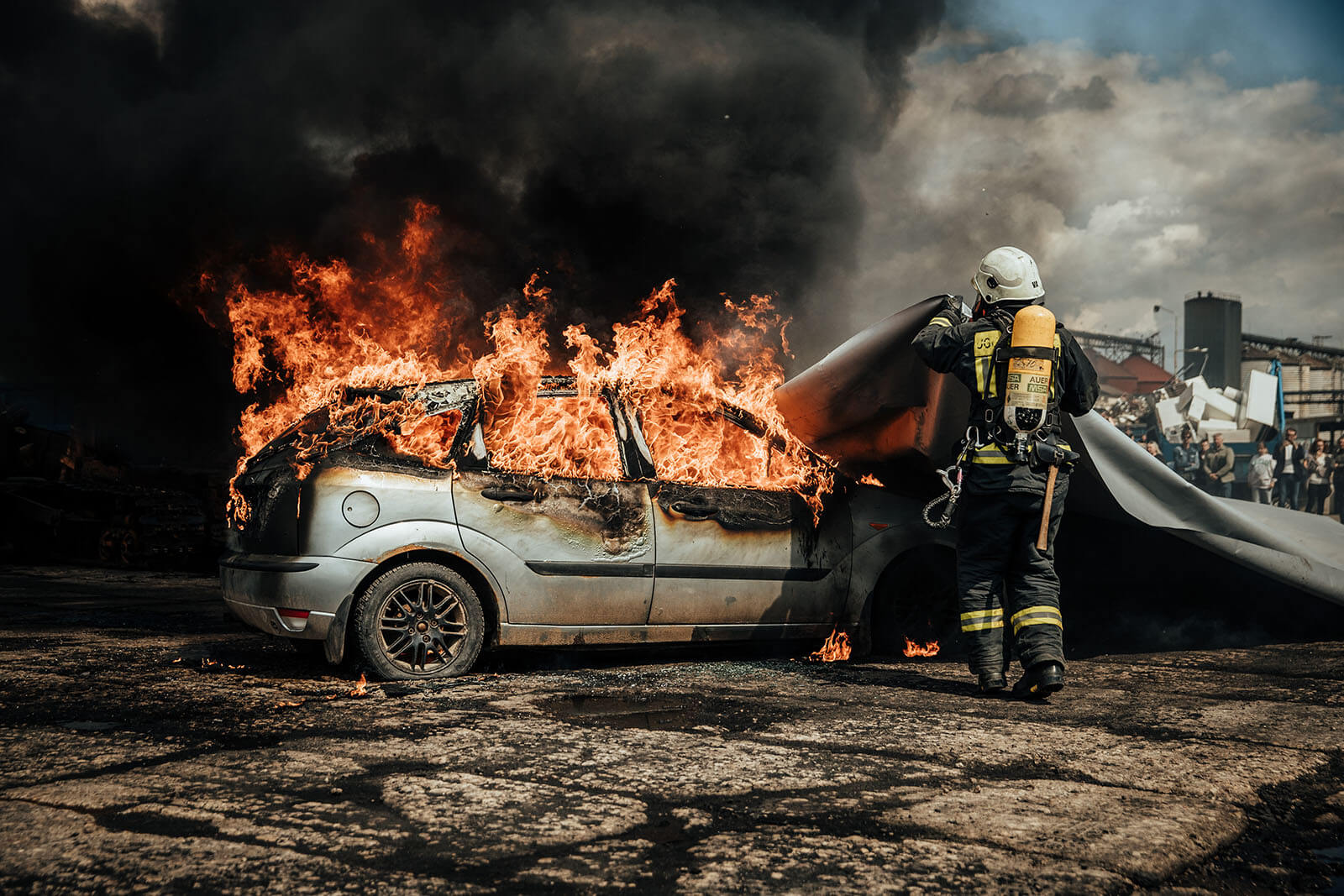 Twee brandweermannen trekken branddeken over brandend voertuig